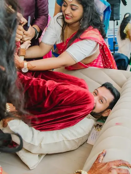 A close-up of the playful struggle during the Joota Chupai. The groom's expression is priceless as he tries to protect his shoes from his new family.