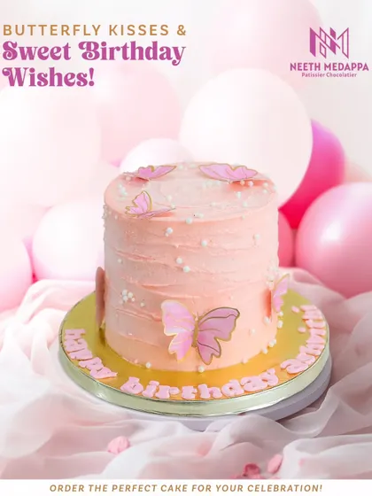 A full view of the pretty pink butterfly cake, set against a backdrop of pink balloons.