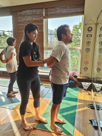 Correcting posture is key. Here, I'm helping a student open his shoulders and find the right alignment in a standing pose, which is crucial for preventing strain.