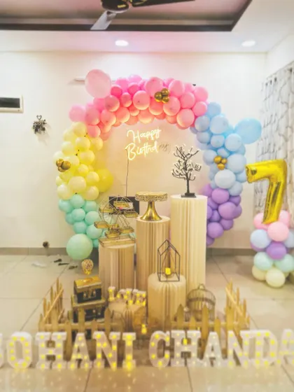 A rainbow-themed 7th birthday party. The balloon arch is made with a spectrum of pastel colors, creating a cheerful and bright atmosphere.