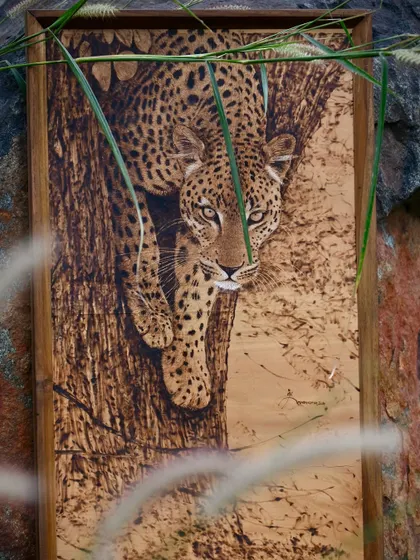 A stunning wood-burned portrait of a leopard descending a tree. This pyrography piece showcases the artist's ability to capture the animal's grace and intensity through detailed heat application.