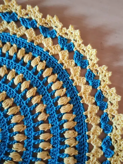 A close-up of the border and stitchwork on my blue and yellow doily. The lacy edge provides a delicate finish to the piece.