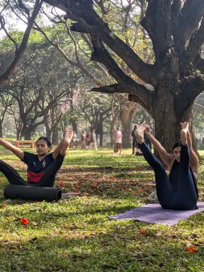 Two students practicing a wide-legged seated forward bend. Our outdoor sessions offer plenty of space to stretch out and connect with your own practice, even in a group setting.