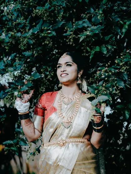 A joyful candid shot of the bride surrounded by lush greenery, her expression full of happiness and anticipation.