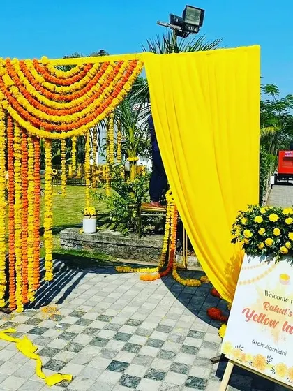 A simple and bright entrance for a Haldi function, made with marigold garlands and a personalized "Welcome to Yellow Land" sign.