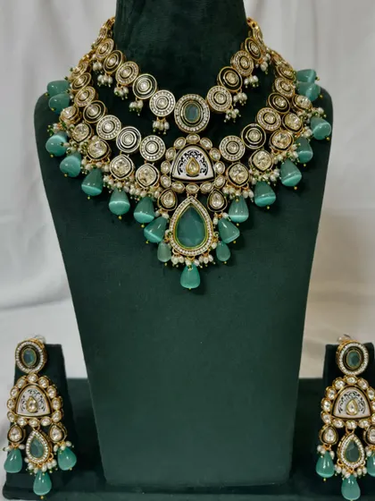 A layered bridal set with a choker and necklace, both adorned with mint green beads and Kundan work. This set includes matching earrings and is available for rent.