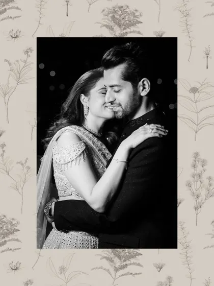 A romantic black and white portrait of a couple embracing, framed by a delicate floral border.