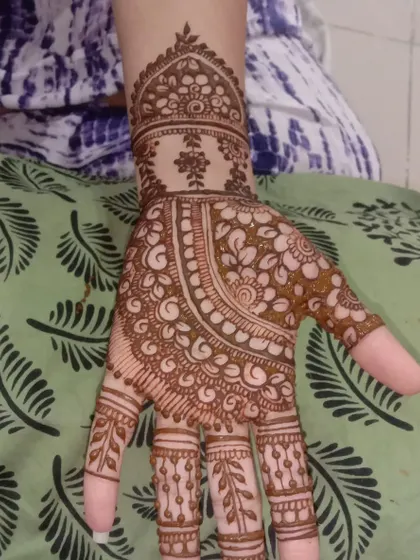 This design covers the back of the hand with delicate, lace-like floral patterns. It's a very feminine and intricate style, suitable for any special occasion.