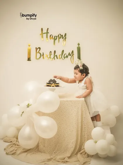Reaching for the cake! This classic white and gold themed birthday setup is perfect for capturing that moment of curiosity before the smashing begins.