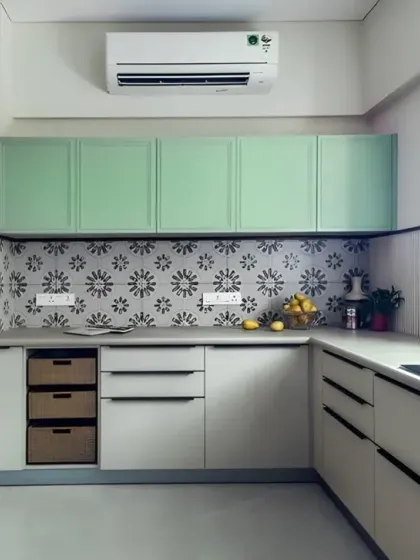 A bright and airy L-shaped kitchen featuring mint green upper cabinets and a patterned tile backsplash. The design includes a tall unit for a built-in oven and microwave, ensuring an efficient kitchen workflow.