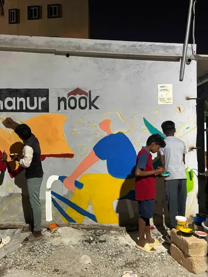The community getting involved in the Sathanur Nook mural, with kids and adults all picking up brushes to add their touch.