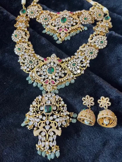 A complete polki and emerald set with a choker, long necklace, and matching jhumkas. This is a perfect choice for a grand reception.