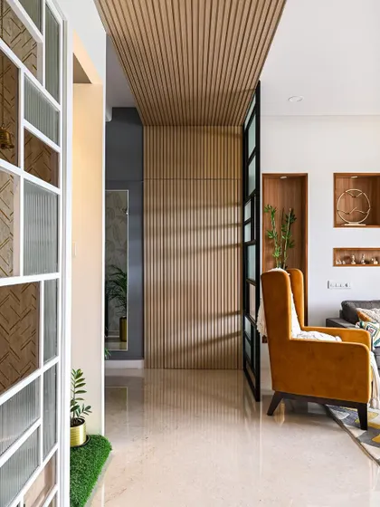 This image shows a clever hidden shoe storage solution. The fluted wooden panel wall in the entryway looks purely decorative, but a section of it is actually a concealed door.