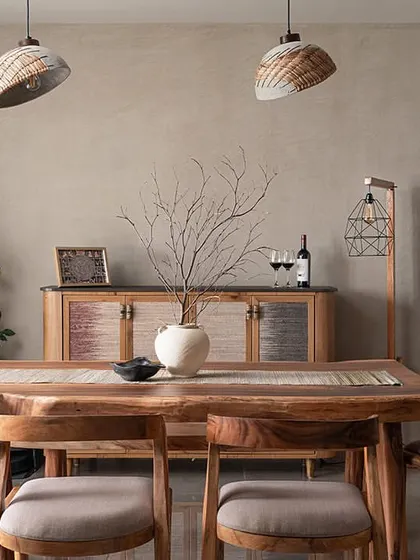This dining room embodies a Wabi-Sabi aesthetic, celebrating natural imperfection. The walls are finished with a soft limewash, creating a beautiful backdrop for the custom live-edge dining table. The crockery console features unique shutters made from banana fibre, and concrete cane pendants add warmth and texture.