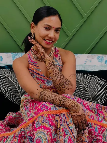 A close-up of Sneha's happy face, her henna-adorned hand adding to her bridal charm.