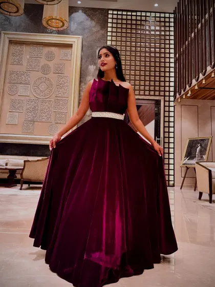 Make a show-stopping entrance at your reception or cocktail party with this luxurious magenta velvet gown. The structured bodice and flowing skirt create a dramatic silhouette, ensuring all eyes are on you. It's a perfect blend of modern design and opulent fabric.