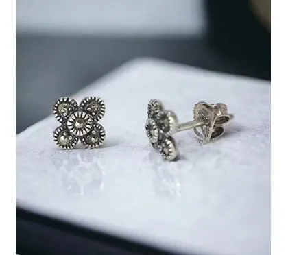 A pair of small, vintage-style studs with intricate marcasite detailing in a four-leaf clover pattern.