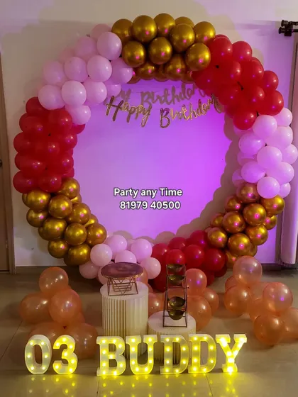 A circular balloon arch in red, white, and gold with light-up letters.