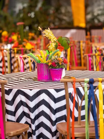 A close-up of the carnival-themed table setting, with a black-and-white chevron tablecloth and chairs adorned with multi-colored ribbons.