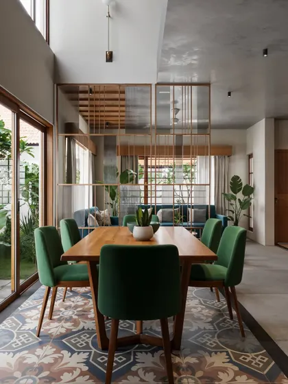 An open-concept dining area that showcases a mix of materials and patterns. The space is defined by traditional patterned floor tiles, which contrast with the modern dining set and a semi-transparent wooden partition that subtly divides the dining and living areas without obstructing the view.