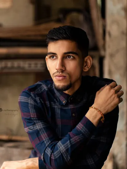 A retro-themed shot of Karan Lakhanpal in a rustic setting. The warm tones and plaid shirt create a timeless, masculine feel.