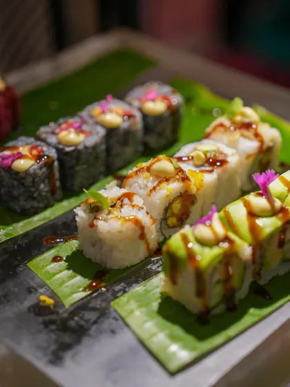 A platter of assorted modern sushi rolls, garnished with edible flowers and creative sauces. This showcases the variety and artistry of our Pan-Asian menu.