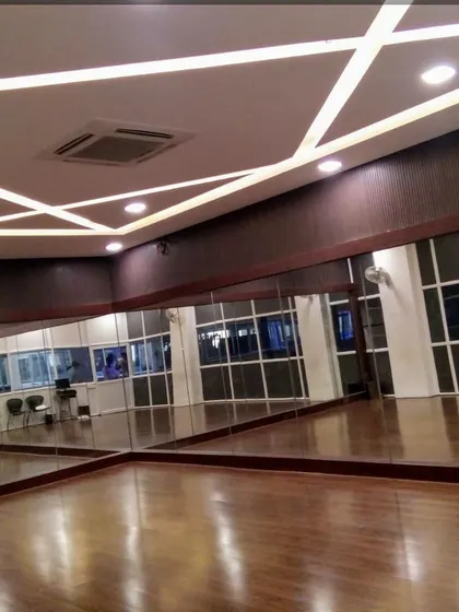 A dance or activity room within Asia Pacific World School, designed with wood flooring, full-length mirrors, and geometric ceiling lighting to create a functional and inspiring space.