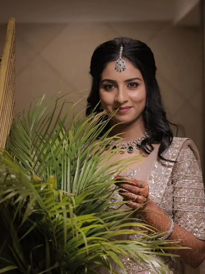 A beautiful portrait from a reception event. The soft lighting highlights the dewy finish of the makeup and the intricate details of her jewelry and outfit.