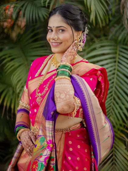 A classic pose showing the beautiful drape of the Paithani Nauvari and the intricate henna design. The makeup is kept fresh and radiant to let the bride's natural beauty shine through.