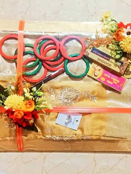 A Karwa Chauth or Teej themed hamper with a suit, bangles, and sindoor.