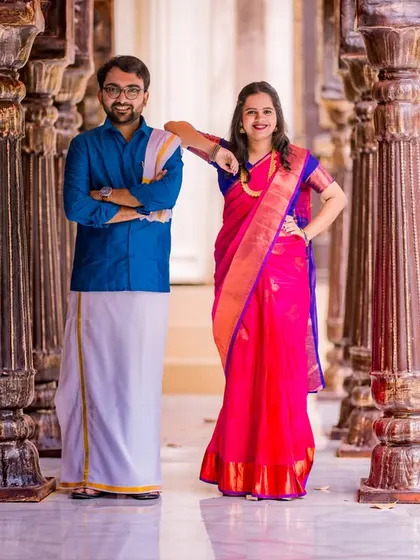 A stylish and confident pose in a corridor of pillars. The couple's contrasting blue and pink traditional outfits create a striking visual.
