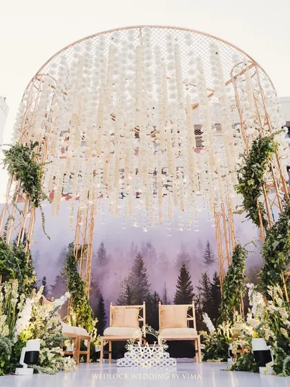 This modern mandap combines a minimalist structure with natural elements. A canopy of hanging white florals against a misty forest backdrop created a serene and breathtaking setting for the ceremony.