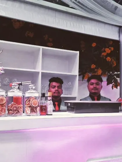 A clean and elegant white bar setup, perfect for a daytime wedding function. The setup includes a custom menu and beautiful floral arrangements, reflecting our promise to deliver a professional and awesome beverage experience.