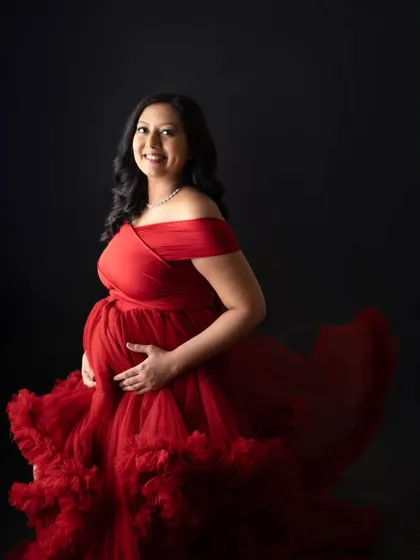 A radiant solo portrait of the mom-to-be. She looks so happy and confident in this incredible red ruffled gown. The simple black background really makes her and the dress the star of the show.