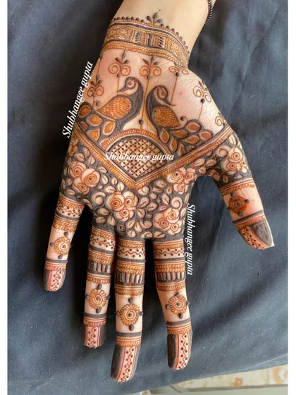 Another view of the twin peacock design. The details on the fingers, with tiny turtles and floral bands, complement the main design on the back of the hand perfectly.
