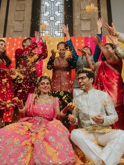 A candid shot of the family showering the couple with flower petals during a colorful Haldi ceremony.