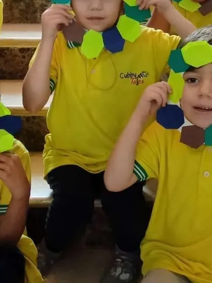 Creativity in action. The children proudly display the colorful paper wreaths they made, an activity that enhances their fine motor skills and allows for self-expression.
