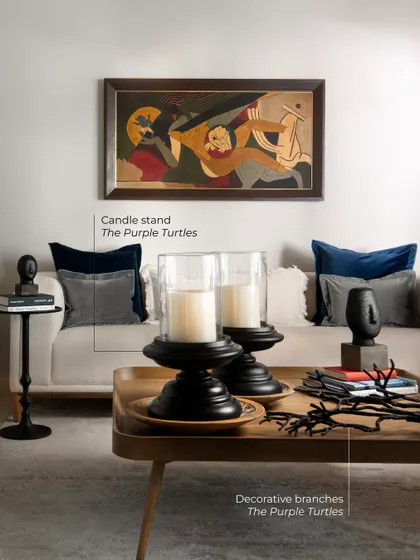 I am never afraid to style with black, because when used with intention, it elevates a room. Here, black candle stands and a side table add depth and definition, grounding the neutral sofa and making the client's artwork shine brighter.