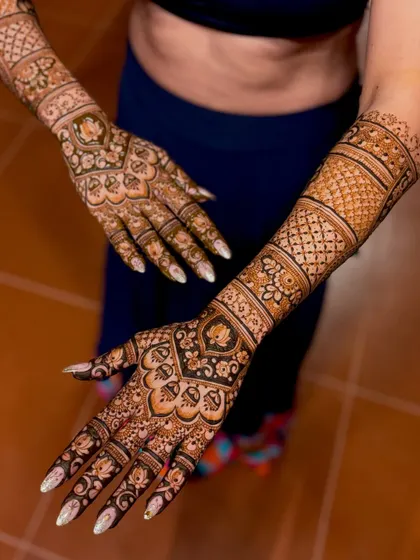 An angled view of a wedding mehendi, showing the detailed work on the arms and hands.