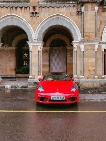 A modern classic. This bright red Porsche adds a splash of colour to the monsoon mood in South Bombay, parked near the iconic Taj Hotel.