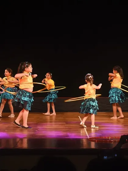 The entire group of young hoop dancers on stage, creating beautiful patterns with their colorful hoops.