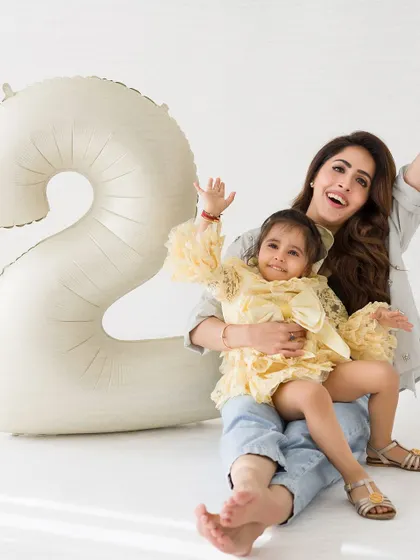 A joyful, celebratory photo of a mother and her two-year-old daughter. Their waving hands and big smiles perfectly capture the fun of a birthday.
