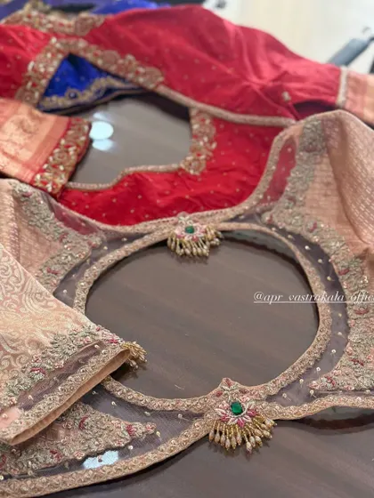 A collection of blouses showcasing various back cutout designs. The one in the foreground features a sheer net panel with a circular cutout and jewellery-style motifs.