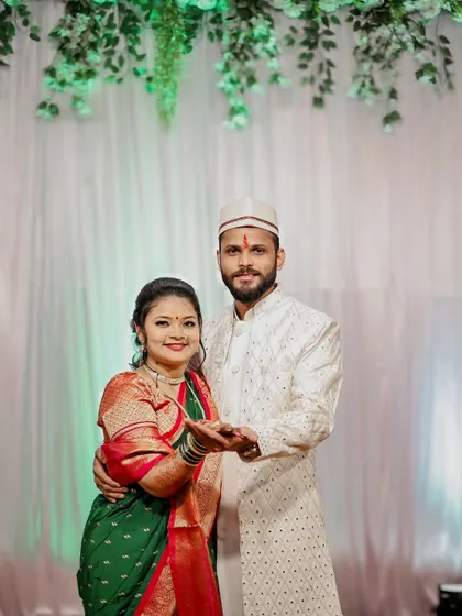 A happy couple posing with their hands outstretched, showing their engagement rings.