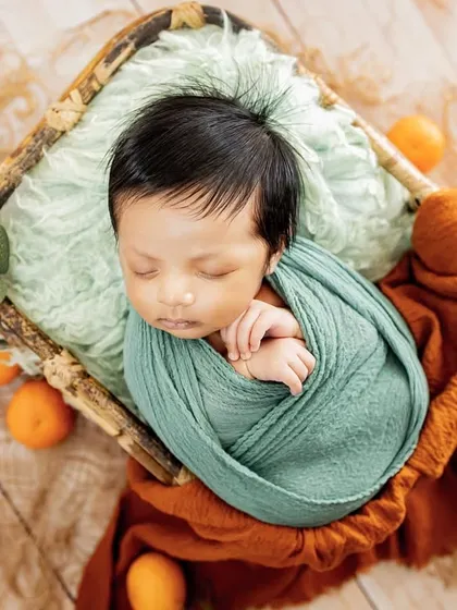 A pop of color with this citrus-themed newborn setup. Using natural elements like these small oranges adds a fresh and unique touch to the classic basket pose.