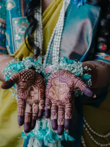 A close up of a baby shower mehendi with a portrait of a mother and child. The design is beautifully complemented by the traditional floral jewelry worn for the ceremony.