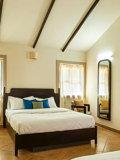 A guest suite at Samavana, designed as a serene retreat from the festivities. The high, vaulted ceiling with exposed beams adds a touch of rustic charm to the modern room.