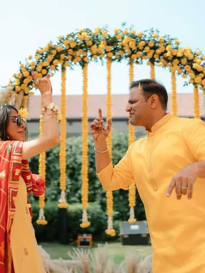 The couple breaking into a dance during their outdoor Haldi ceremony, full of energy and happiness.