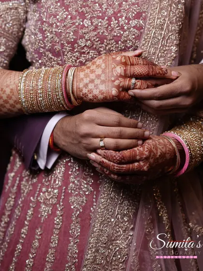 A close-up on the hands, showing the engagement rings and intricate henna. This detail shot tells a story of commitment and tradition.