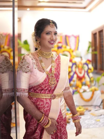 This bride is ready for her ceremony, showcasing a beautiful look with a bright pink lip that pops against her elegant saree. The makeup is designed to be long-lasting and picture-perfect.